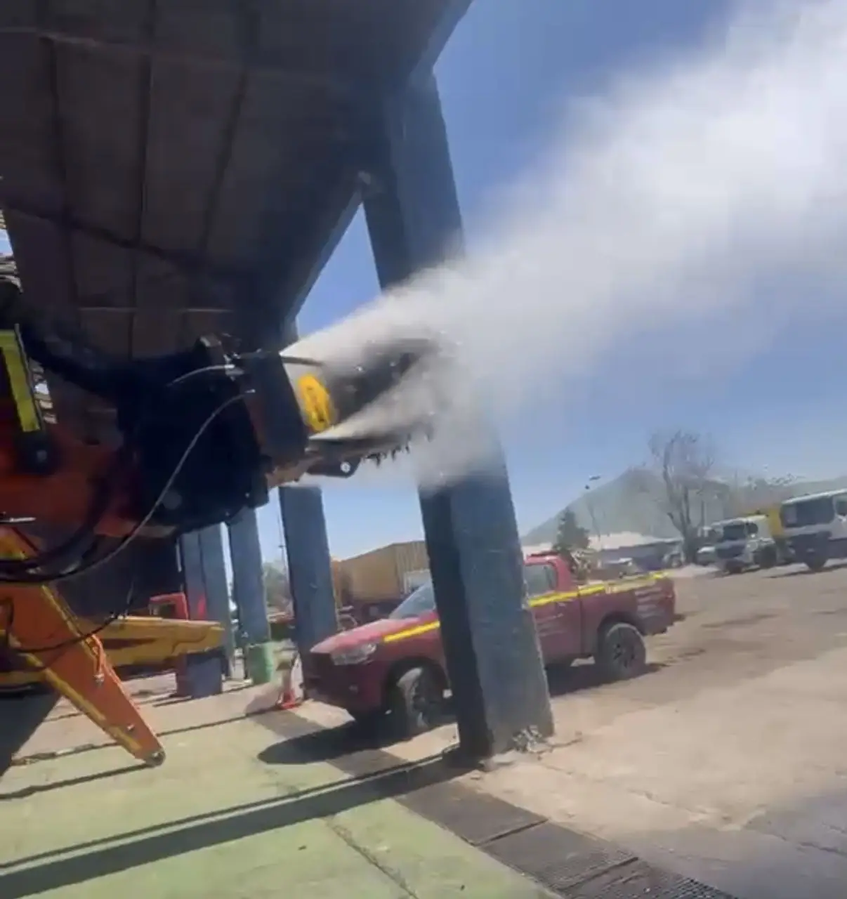 Supresor de polvo montado en el brazo de una excavadora, lanzando agua nebulizada
